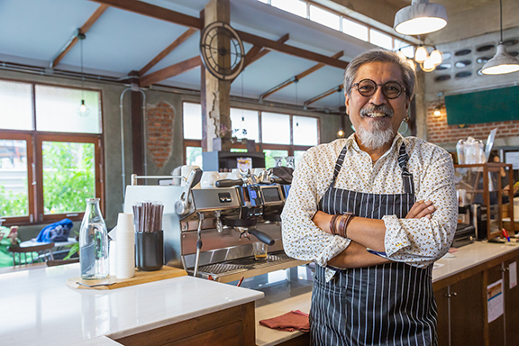 Direct Deposit male worker in kitchen restaurant cafe smiling