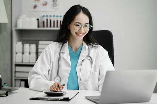 doctor looking at laptop and using calculator