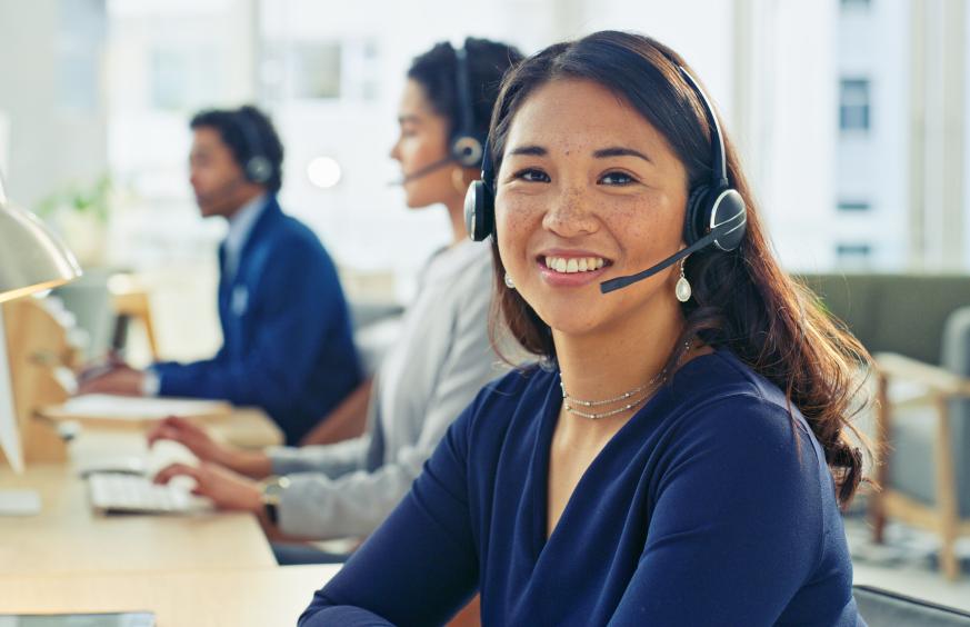 A group of young professionals working in a modern office environment engaging with clients using headsets.