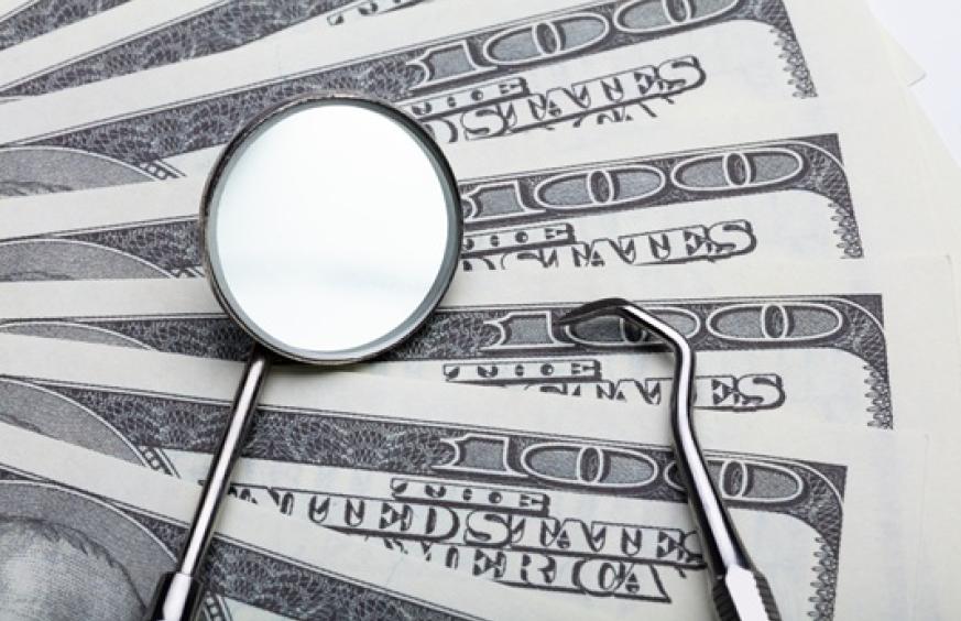 dental instruments atop several 100 dollar bills