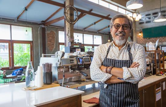 Direct Deposit male worker in kitchen restaurant cafe smiling