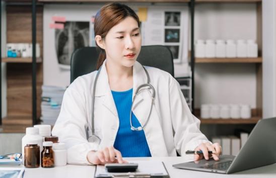 doctor using calculator and laptop