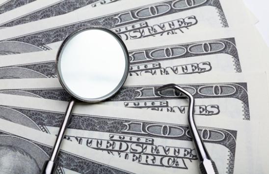 dental instruments atop several 100 dollar bills
